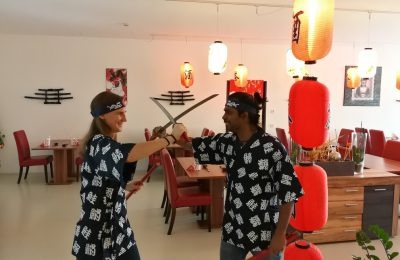 Spaß im Sushi-Kurs – Teilnehmer in Kimono mit Samurai-Schwertern
